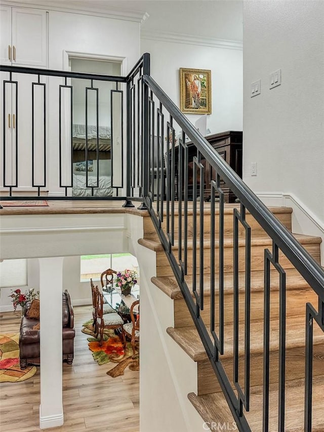 staircase with crown molding and wood finished floors