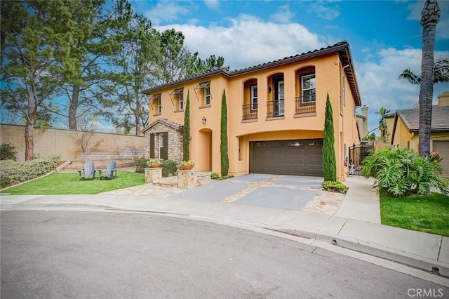 mediterranean / spanish house featuring stucco siding, an attached garage, fence, a balcony, and driveway