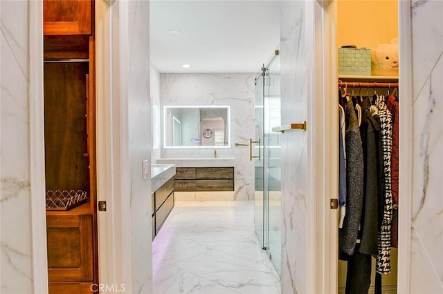 bathroom featuring vanity, a spacious closet, a marble finish shower, marble tiled floors, and recessed lighting