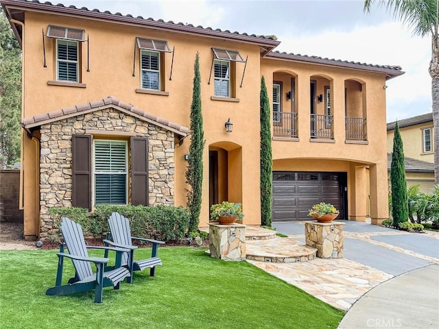 mediterranean / spanish-style home featuring asphalt driveway, stucco siding, a balcony, and an attached garage