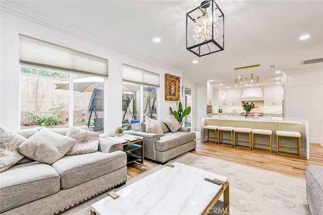 living area featuring ornamental molding, recessed lighting, and light wood-type flooring