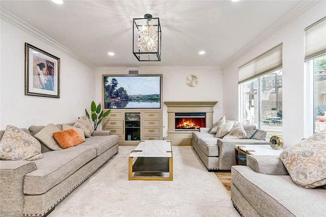 living room featuring ornamental molding, recessed lighting, a warm lit fireplace, and light wood-style flooring