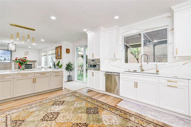 kitchen with stainless steel appliances, a sink, light wood-style floors, recessed lighting, and light countertops