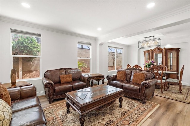 living area with light wood-style floors, healthy amount of natural light, a chandelier, recessed lighting, and crown molding