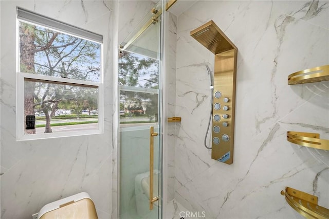 bathroom with a marble finish shower and toilet