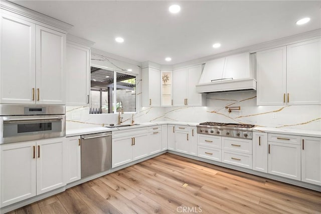 kitchen with a sink, appliances with stainless steel finishes, custom exhaust hood, white cabinetry, and recessed lighting