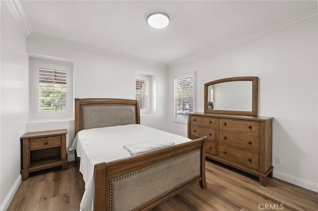 bedroom featuring crown molding, multiple windows, light wood-style flooring, and baseboards