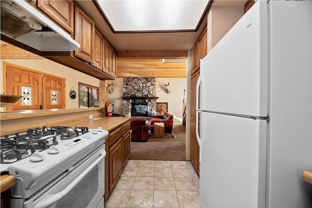 kitchen with brown cabinets, light tile patterned floors, light countertops, white appliances, and under cabinet range hood