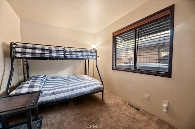 carpeted bedroom featuring visible vents, a textured wall, and a textured ceiling