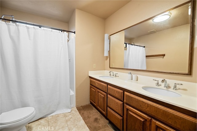 bathroom with double vanity, tile patterned flooring, a sink, and toilet