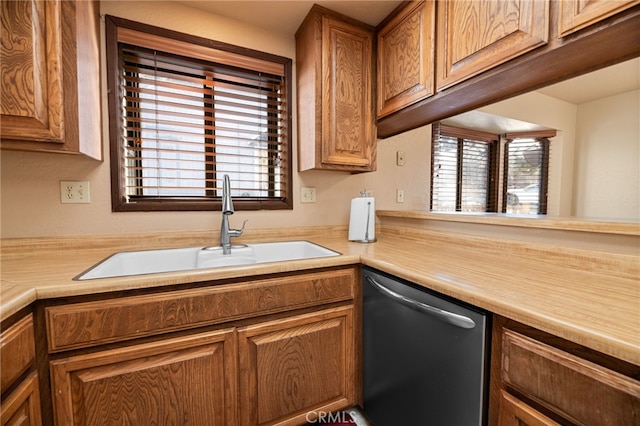 kitchen featuring light countertops, stainless steel dishwasher, a sink, and a healthy amount of sunlight