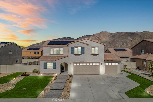 mediterranean / spanish house with stucco siding, a front yard, fence, and a tiled roof