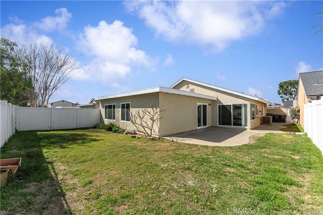 back of house featuring central AC unit, a fenced backyard, a lawn, stucco siding, and a patio area