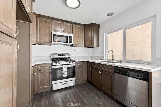 kitchen featuring appliances with stainless steel finishes, light countertops, a sink, and dark wood-style floors