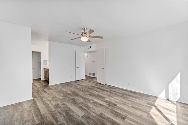 unfurnished bedroom featuring visible vents, ensuite bath, baseboards, and wood finished floors