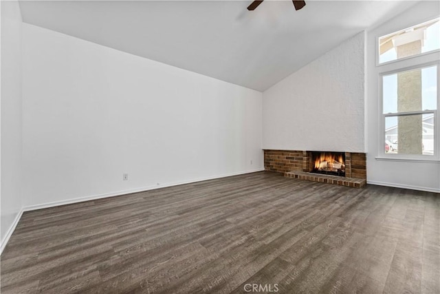 unfurnished living room featuring baseboards, lofted ceiling, dark wood-style floors, ceiling fan, and a brick fireplace