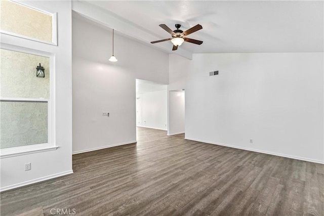 empty room featuring dark wood-style flooring, visible vents, ceiling fan, high vaulted ceiling, and baseboards