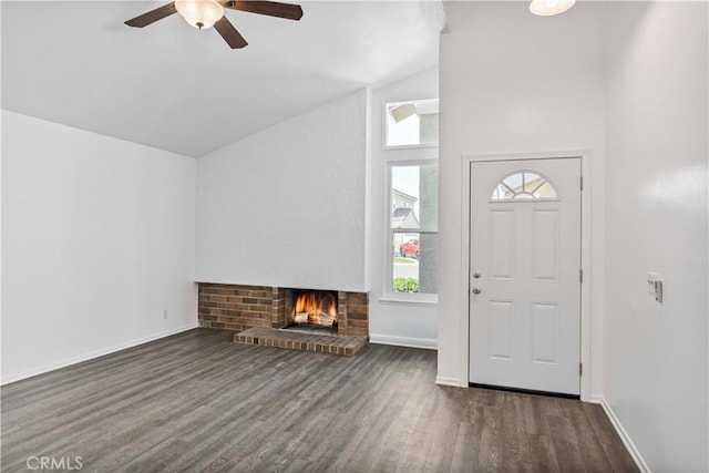 foyer featuring a fireplace, wood finished floors, a ceiling fan, baseboards, and vaulted ceiling