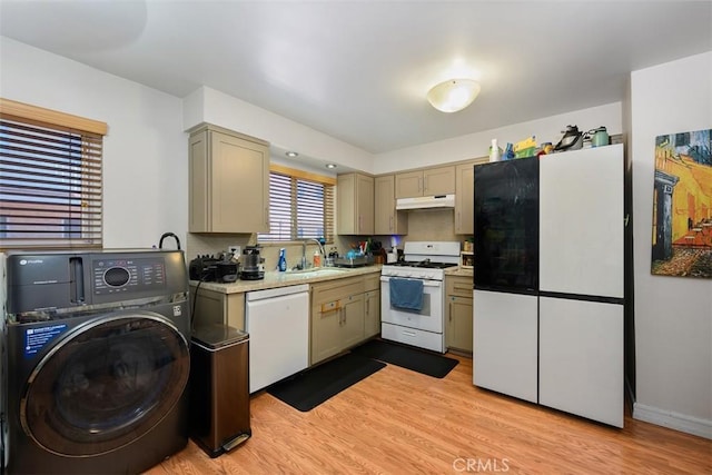 kitchen with under cabinet range hood, a sink, washer / clothes dryer, white appliances, and light countertops