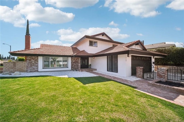 rear view of house with a chimney, stucco siding, a lawn, an attached garage, and fence