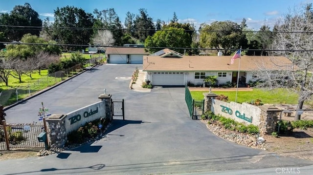 ranch-style home featuring a garage, a fenced front yard, and a gate