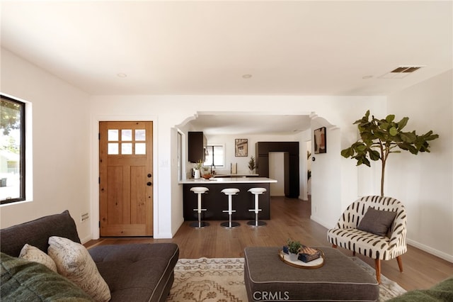 living room with wood finished floors, visible vents, and a healthy amount of sunlight