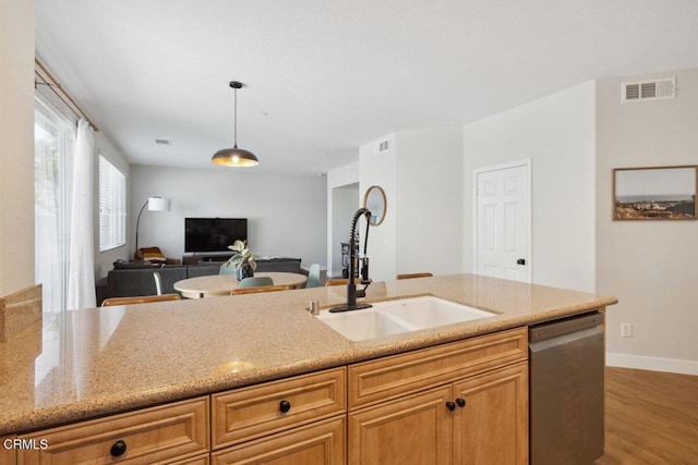 kitchen featuring visible vents, dishwasher, wood finished floors, hanging light fixtures, and a sink