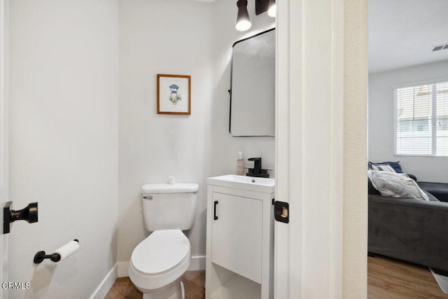 bathroom with ensuite bathroom, toilet, wood finished floors, vanity, and baseboards