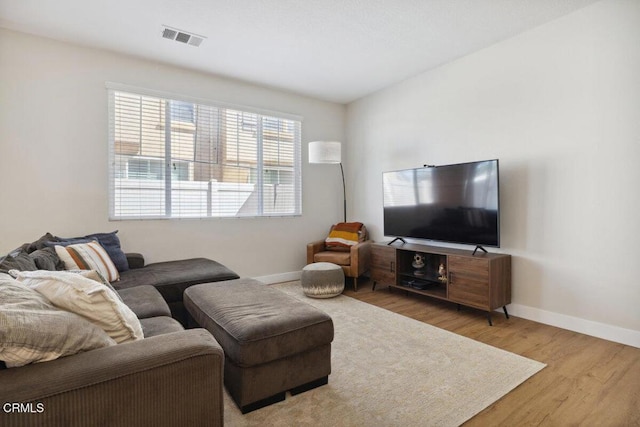 living area featuring wood finished floors, visible vents, and baseboards