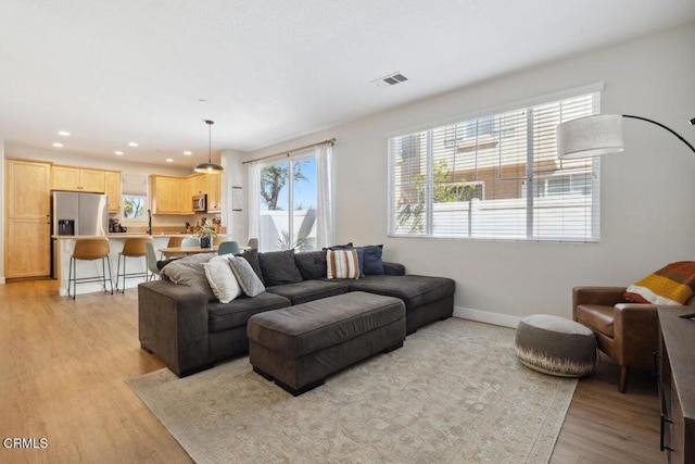 living area with light wood-style flooring, recessed lighting, visible vents, and baseboards