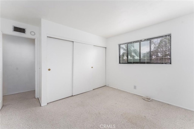 unfurnished bedroom featuring carpet floors, visible vents, and a closet