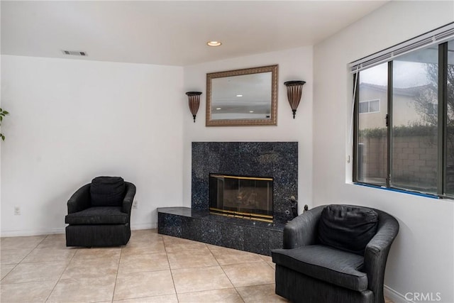 living area featuring baseboards, visible vents, a premium fireplace, and tile patterned floors