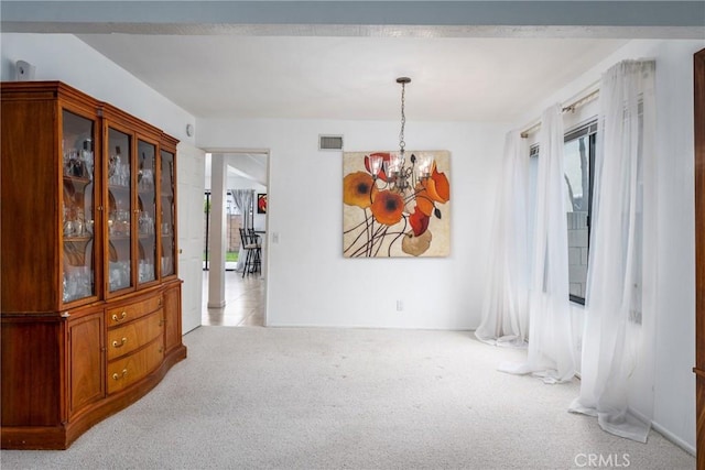 dining space with plenty of natural light, visible vents, a chandelier, and light colored carpet