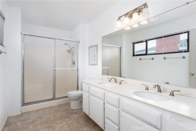 bathroom with a stall shower, a sink, toilet, and double vanity