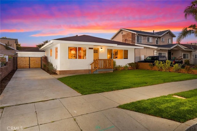 view of front of house featuring a gate, fence, a front lawn, and stucco siding