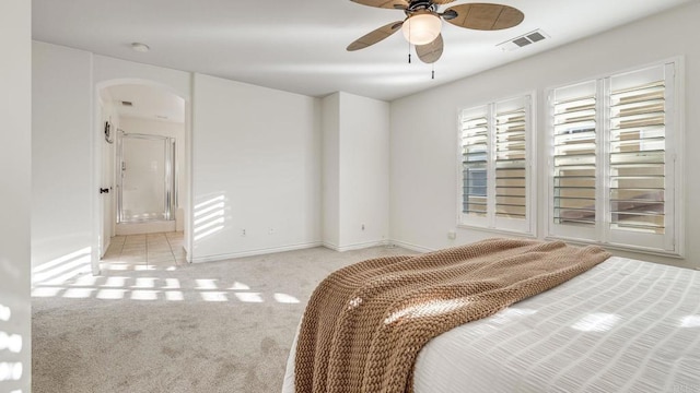 carpeted bedroom with visible vents, arched walkways, and baseboards