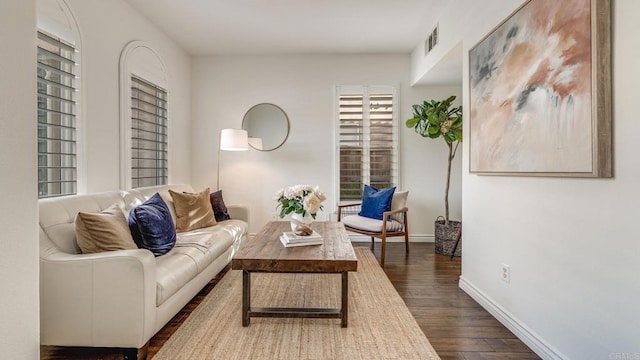 living room featuring visible vents, dark wood-style floors, and baseboards