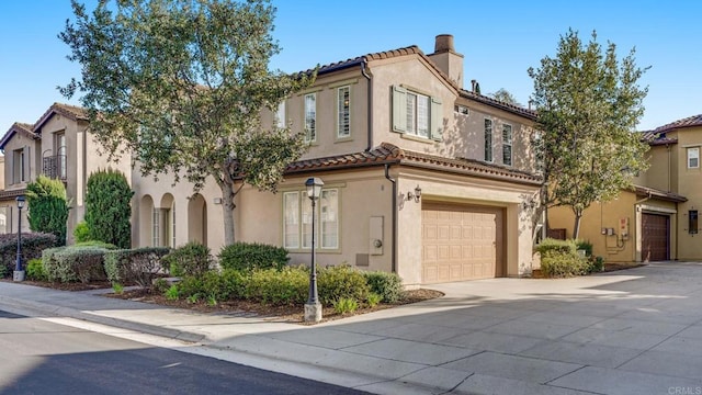 mediterranean / spanish house with a chimney, stucco siding, concrete driveway, a garage, and a tiled roof