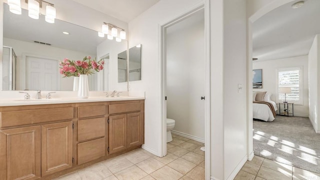 ensuite bathroom featuring a sink, ensuite bathroom, toilet, and double vanity