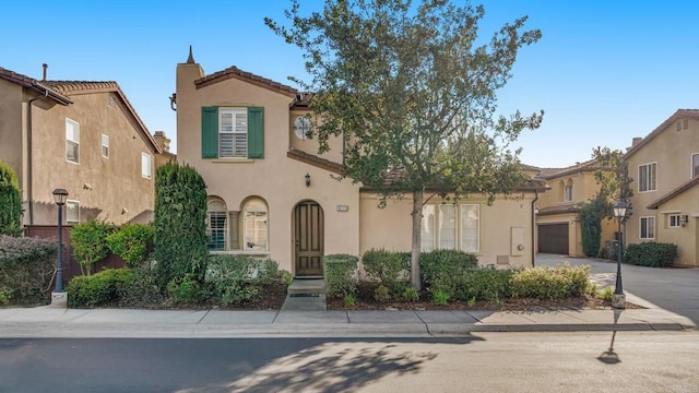 mediterranean / spanish home featuring stucco siding, a garage, driveway, and a tile roof