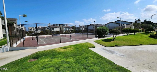 surrounding community with a tennis court, a lawn, fence, and a residential view