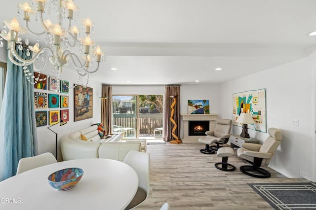 living area with a chandelier, recessed lighting, wood finished floors, baseboards, and a brick fireplace