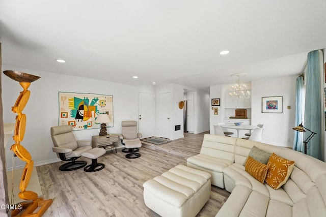 living room featuring a notable chandelier, baseboards, wood finished floors, and recessed lighting