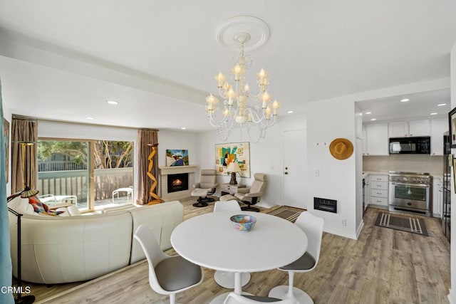 dining room with a warm lit fireplace, light wood-type flooring, and recessed lighting