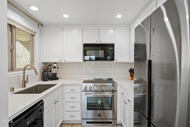 kitchen featuring black appliances, backsplash, a sink, and white cabinetry