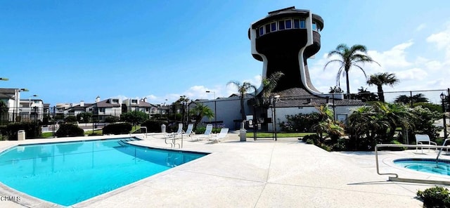 pool featuring a patio, fence, a residential view, and a hot tub