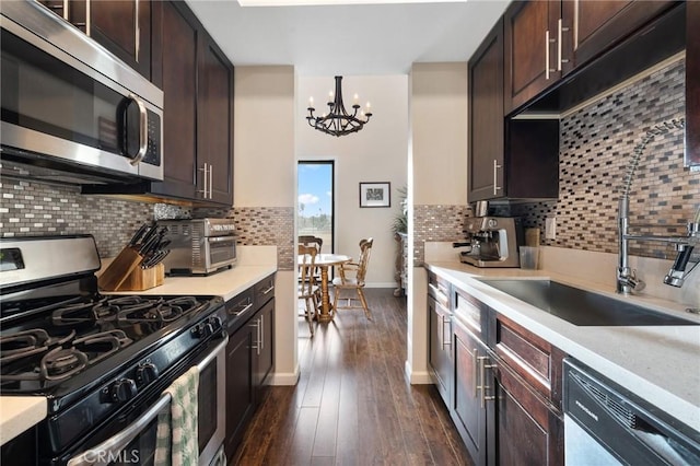 kitchen featuring dark brown cabinets, appliances with stainless steel finishes, dark wood-style flooring, and a sink