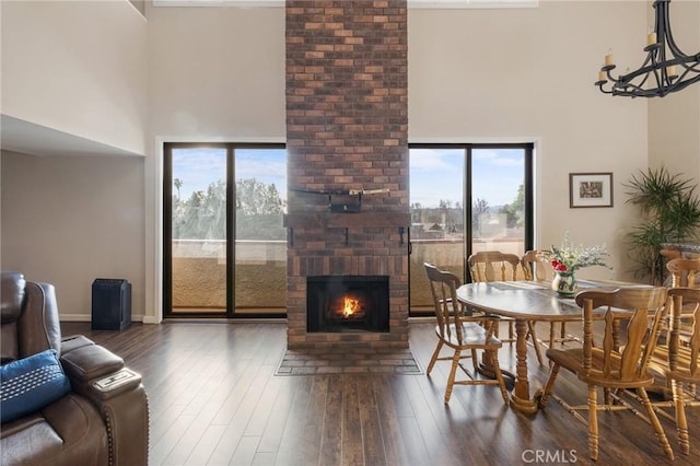 dining area with wood-type flooring, a fireplace, a high ceiling, and baseboards