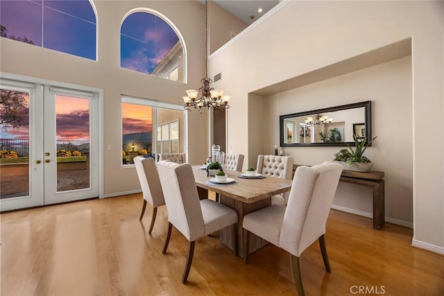 dining area with a chandelier, french doors, wood finished floors, and baseboards