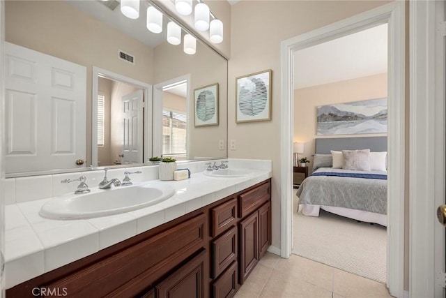 ensuite bathroom with double vanity, visible vents, a sink, and tile patterned floors